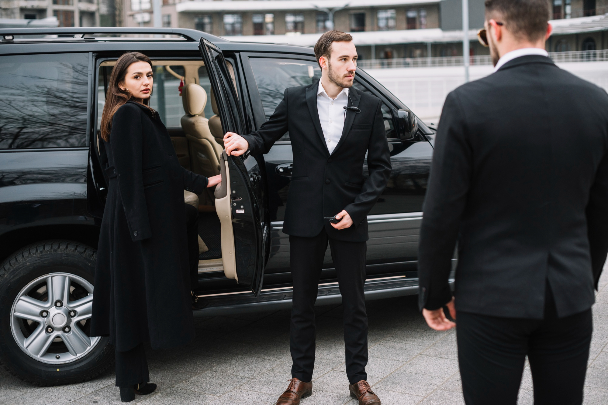 Professional chauffeur opening the door of a luxury car